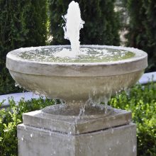 A picture of a stone water fountain pouring water from a large bowl.